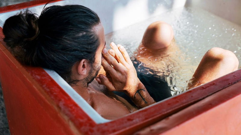 A person relaxing in an outdoor cold water immersion tub / ice bath